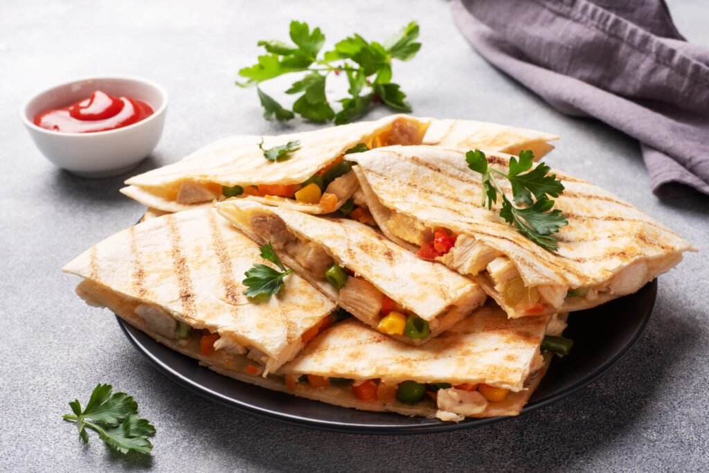 Triangular slices of a Mexican quesadilla with the sauce