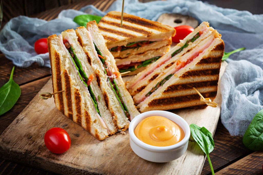 Club sandwich with ham, tomato, cheese and spinach. Grilled panini